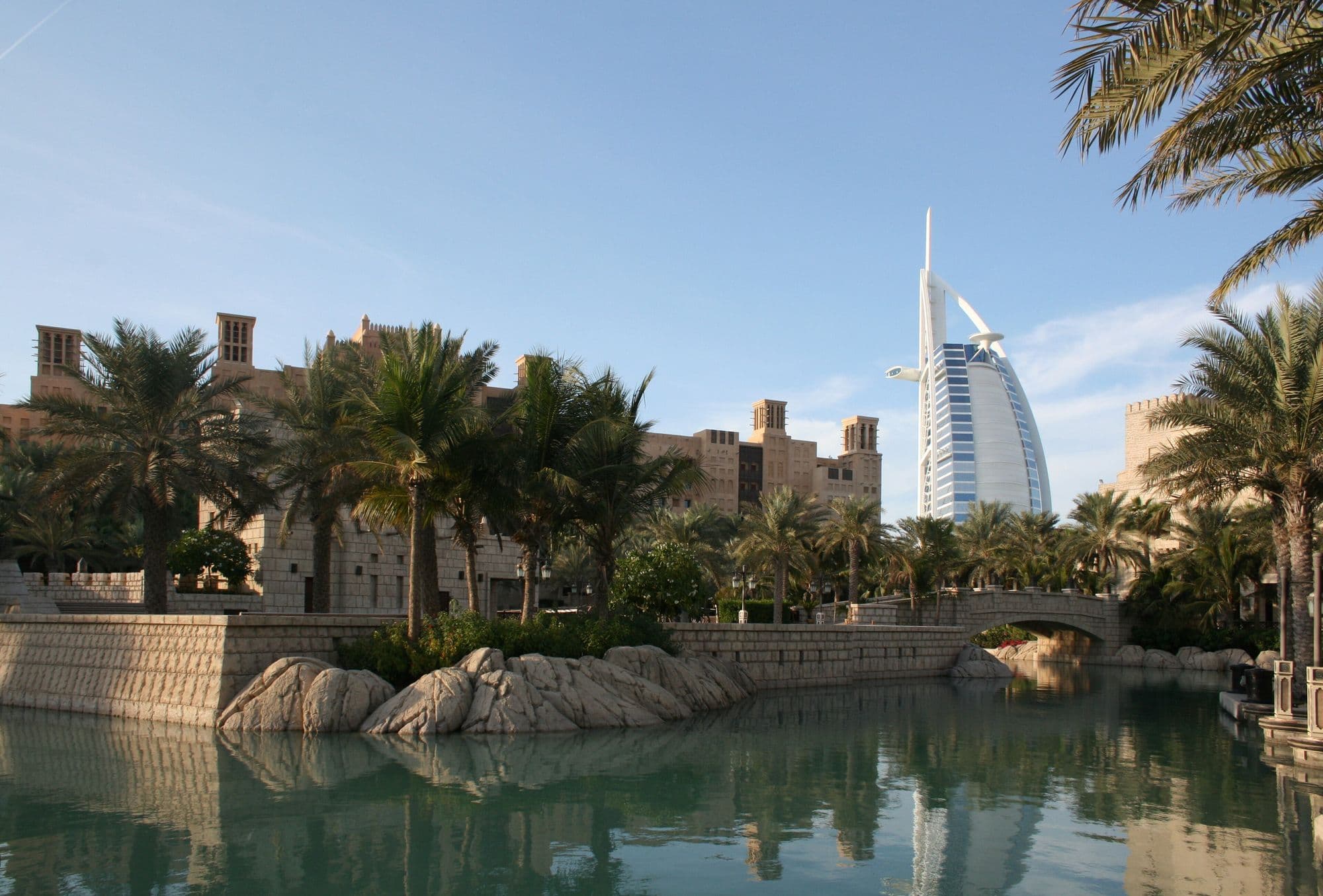 The sail-shaped Burj Al Arab beyond palm trees and a canal at Madinat Jumeirah.