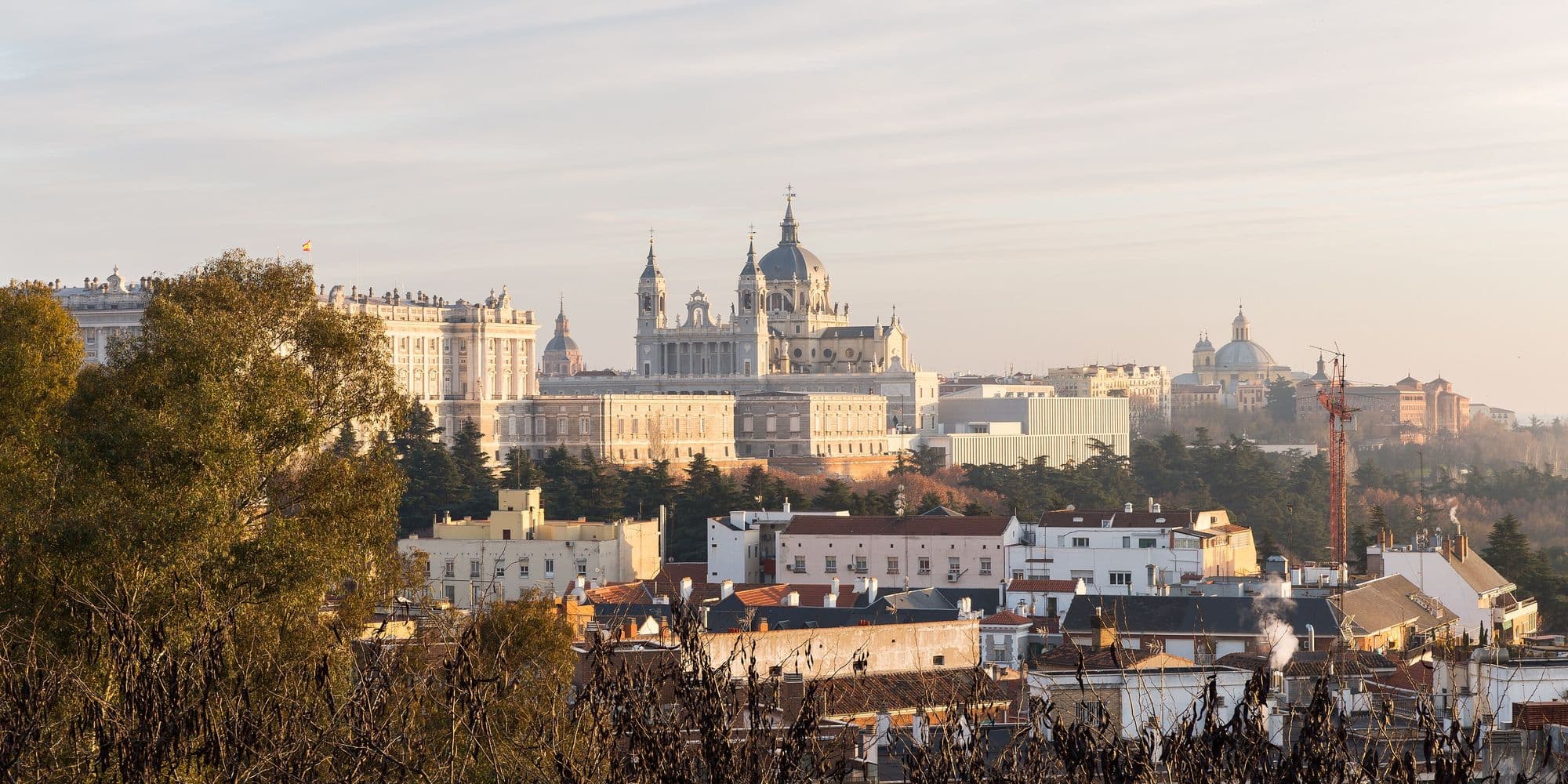 Almudena Cathedral and the Royal Palace on the skyline above the roofs of Madrid, in low winter light.
