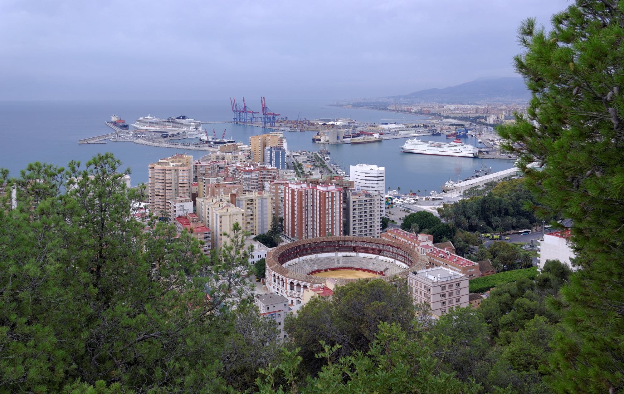 Málaga from Gibralfaro: the bullring and the port below, the bay and the mountains beyond.